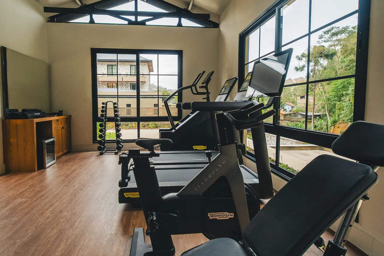 Esteiras e equipamento de cardio voltados para janelas altas